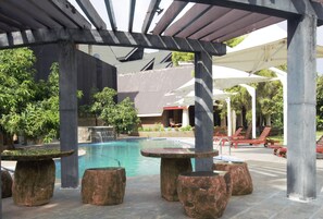 Alberca al aire libre, sombrillas en la alberca y camastros