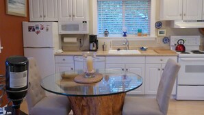 A compact kitchen with white cabinets, a glass-top dining table, and a coffee maker. - MontanAloha, a hideaway just North of Downtown Missoula (Missoula)