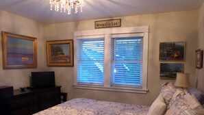 A bedroom with a bed, a television, a desk, and a window with blinds. - MontanAloha, a hideaway just North of Downtown Missoula (Missoula)