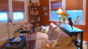 A living room with a sofa, a coffee table, a bookshelf, and a window with blinds. - MontanAloha, a hideaway just North of Downtown Missoula (Missoula)