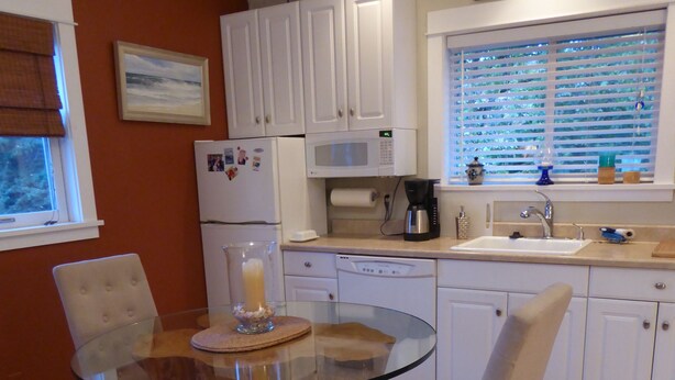 A modern kitchen with white cabinets, a glass-top dining table, and a coffee maker. - MontanAloha, a hideaway just North of Downtown Missoula (Missoula)