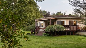 A single-story house with a covered porch, a front door, and a small front yard. - The Round House at Pleasant Hill, Near Mohican & Snow Trails (Perrysville)