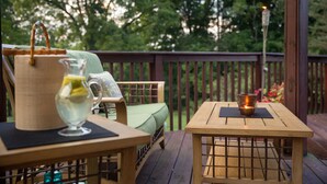 A wooden deck with a table and chairs, a candle in a lantern, and a pitcher of water. - The Round House at Pleasant Hill, Near Mohican & Snow Trails (Perrysville)