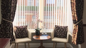 A room with two armchairs, a small table, and a window with vertical blinds. - Doriam (Bridlington)