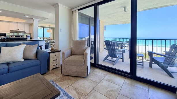 Ein Balkon mit Blick auf das Meer, ein blaues Sofa, ein beiger Sessel und ein Holztisch.