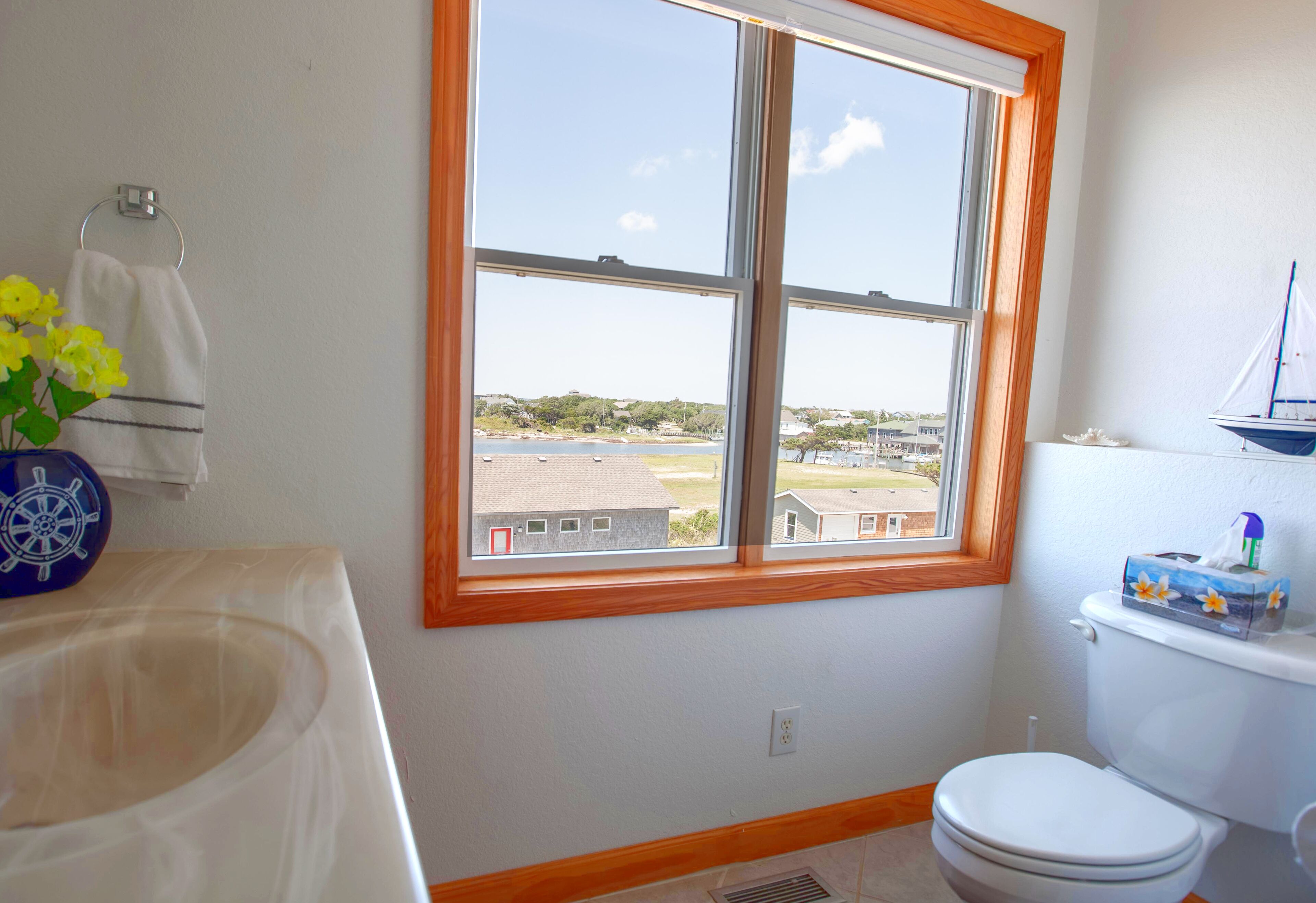Ein Badezimmer mit Fenster, Toilette und Waschbecken.