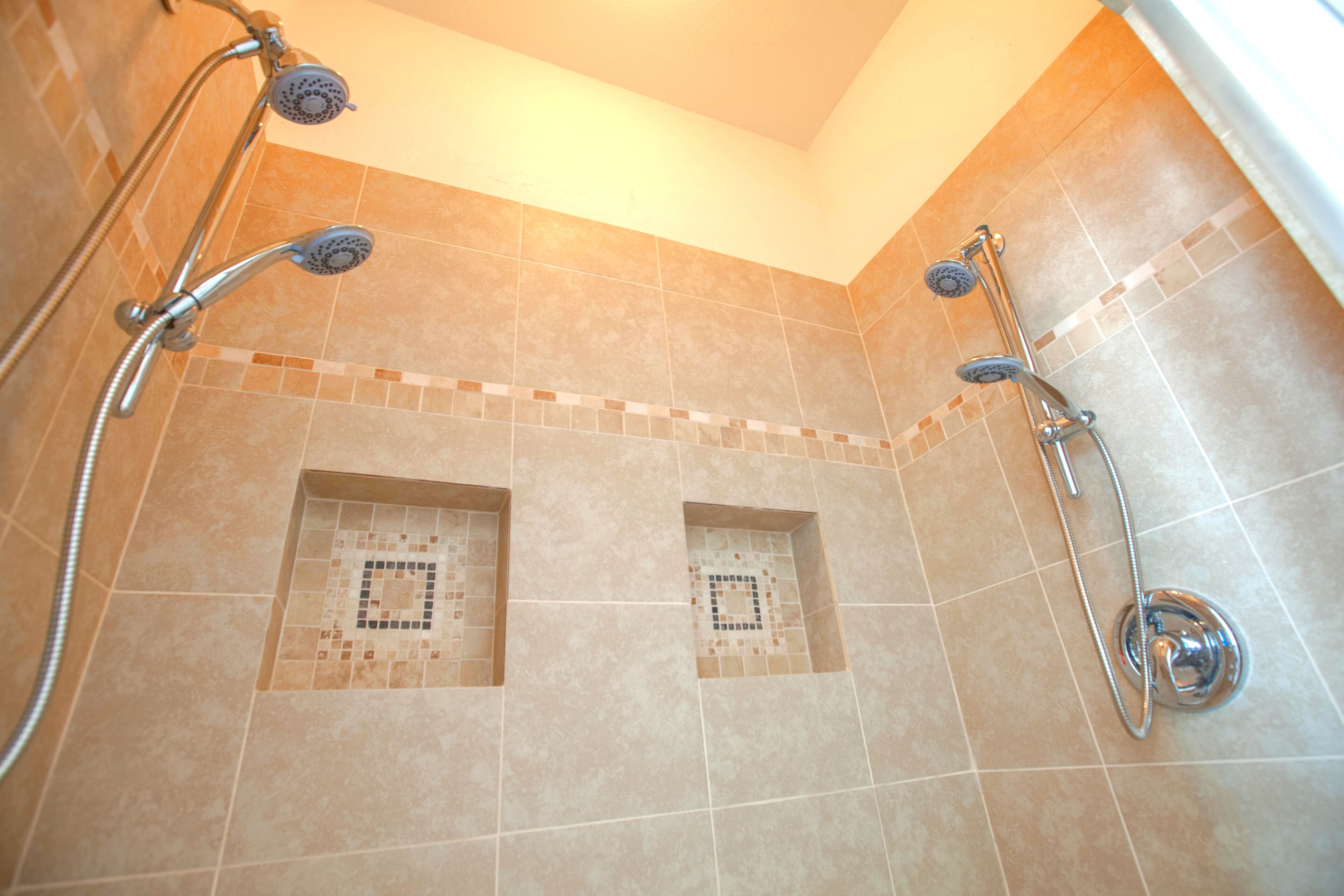 A shower area with two showerheads and a handheld shower attachment.