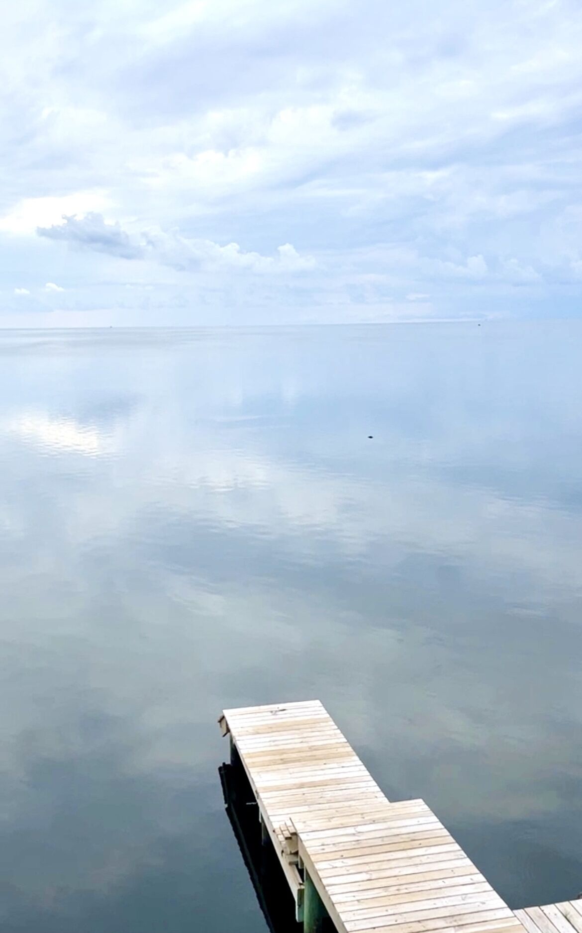 Une jetée en bois s’étendant sur une étendue d’eau calme, sous un ciel dégagé.