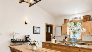 A wooden dining table with benches, a kitchen area with wooden cabinets, and a hanging light fixture. - Modern, Quality 4BR Near Downtown (Durham)
