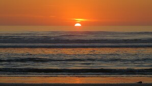Un atardecer sobre el océano con olas acercándose a la orilla.