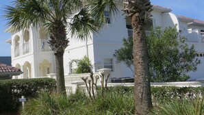 Un edificio blanco con un balcón y una palmera al frente.
