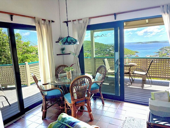 A balcony with a table and chairs, a hanging light fixture, and a view of a coastal landscape.