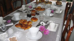 A breakfast setting with pastries, cups, and a table set for four. - Chambre d'Hôtes L'Imprevu (Cucq)