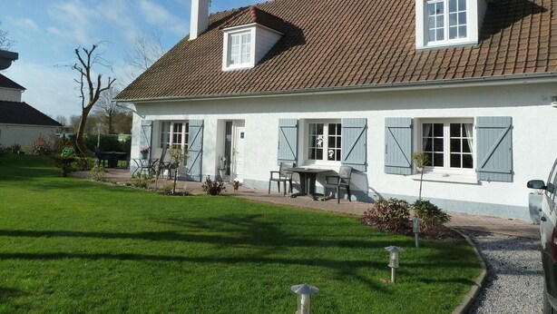 A two-story house with a tiled roof, a front porch with a table and chairs, and a well-maintained lawn. - Chambre d'Hôtes L'Imprevu (Cucq)