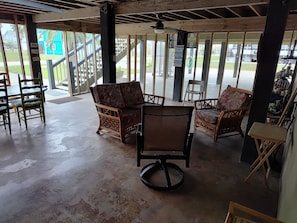 Relax in a serene space with wicker chairs and a ceiling fan, surrounded by windows offering a view.