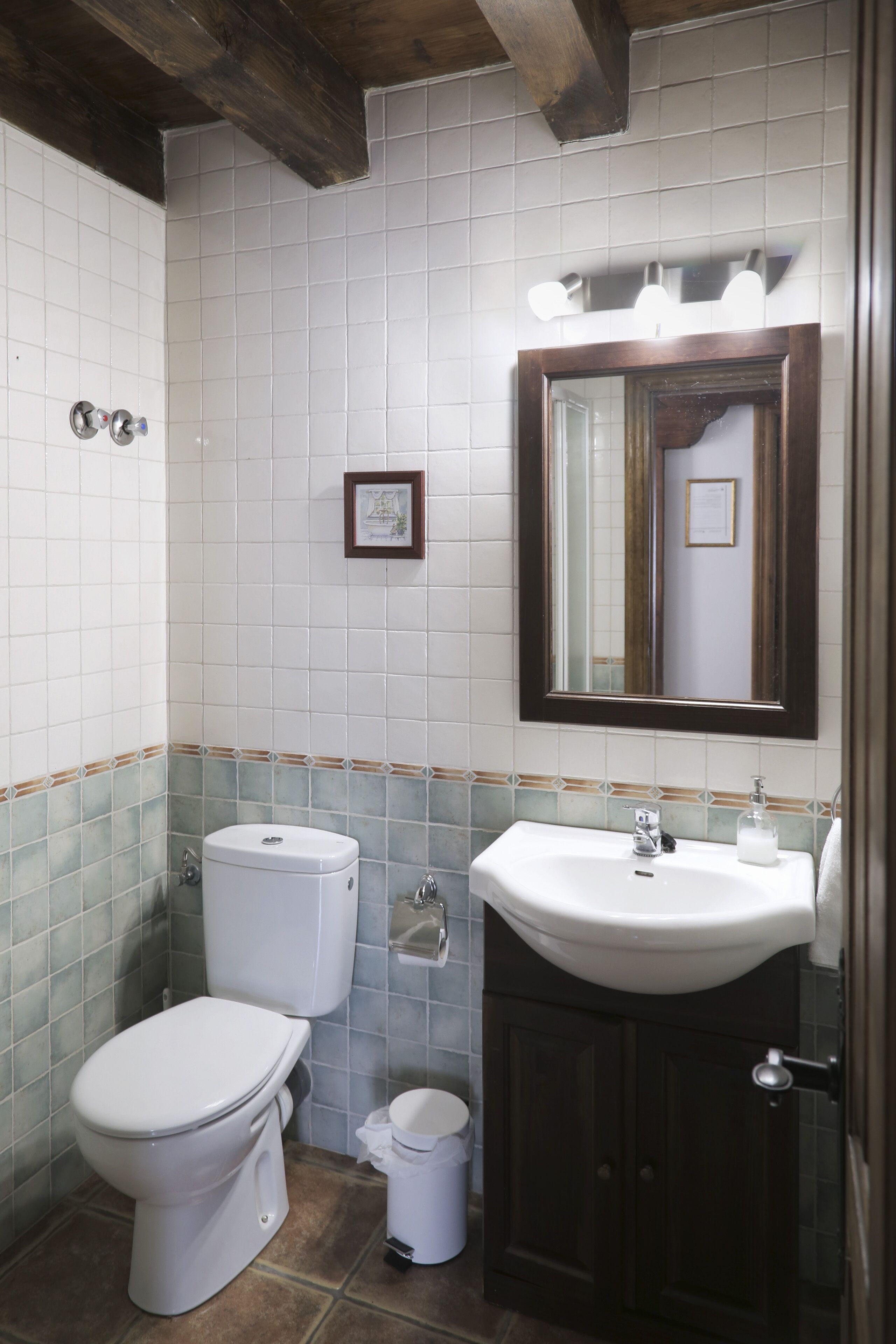 A bathroom with a toilet, sink, and mirror.