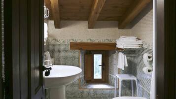 Une salle de bain avec un plafond en bois, un lavabo, des toilettes et une petite fenêtre.