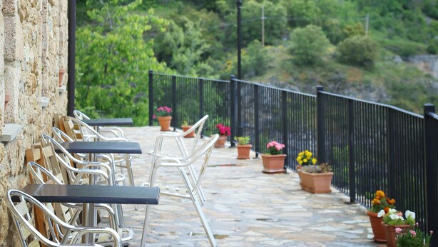 A terrace with outdoor seating, stone flooring, and a view of a mountainous landscape. - Hotel Rural La Puebla (Valle de Sedano)