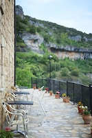 Una terraza con mobiliario exterior, suelo de piedra y vistas a un paisaje montañoso.