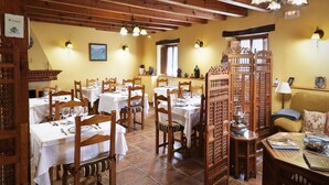 A dining area with wooden tables and chairs, a chandelier, and a decorative partition. - Hotel Rural La Puebla (Valle de Sedano)