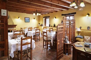 Un comedor con mesas y sillas de madera, una araña y un separador decorativo.