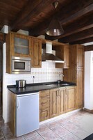 Una cocina con armarios de madera, un microondas de acero inoxidable, un lavamanos y un refrigerador.