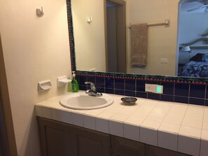 A bathroom with a white sink, a mirror, and a tiled backsplash.