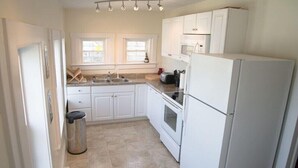 A compact kitchen with white cabinets, a sink, a stove, and a refrigerator. - Garfield Guest House - Hawksbill Suite (Luray)