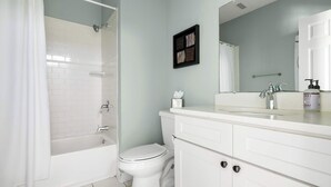 A bathroom with a bathtub, toilet, and a sink with a mirror above it.
