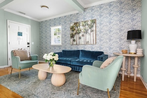 Un salon avec un canapé bleu, une table basse ronde et un tapis à motifs.