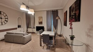 Una sala de estar moderna con sofá, mesa de comedor, televisor y elementos decorativos.