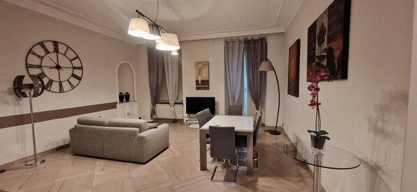 A modern living room with a sofa, dining table, TV, and decorative items.