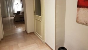 Un pasillo con una puerta, un sofá y un cuadro en la pared.