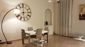 Un comedor moderno con una mesa redonda y sillas, una lámpara de pie, un reloj y una mesa de centro de vidrio.