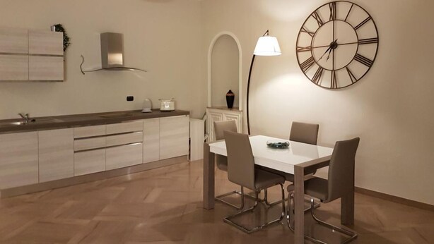 Una cocina moderna con comedor, que presenta un reloj de pared grande, luces colgantes y un diseño minimalista.
