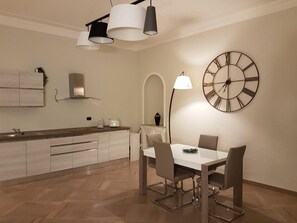 Una cocina moderna con comedor, que incluye un reloj y luces colgantes.