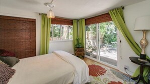 Een slaapkamer met een bed, nachtkastje, lamp en een raam met gordijnen.