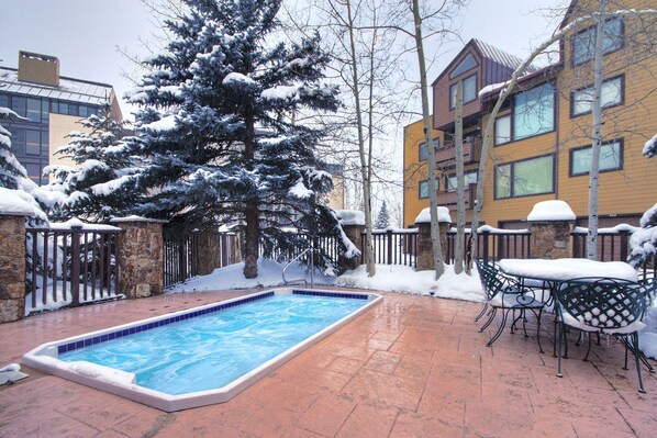 Relax by the rectangular pool surrounded by a deck and snow-covered trees.