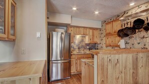 Une cuisine moderne avec des meubles en bois, un réfrigérateur en acier inoxydable et un pare-feu décoré d’un motif de carreaux.