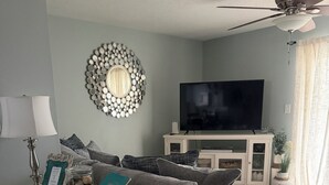 A living room with a sofa, a television, a decorative mirror, and a ceiling fan. - Recently-Remodeled Destin Townhouse. Extended Stay Discount Nov-Feb (Miramar Beach)