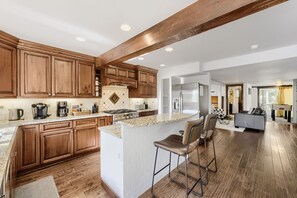 A spacious kitchen with wooden cabinets, a granite countertop, and a central island with bar stools. - High Point Chateau 4 Bedroom Home by RedAwning (Breckenridge)