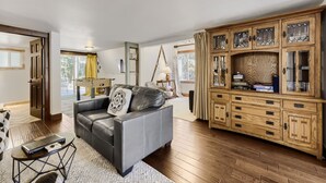 A living room with a leather sofa, a wooden cabinet with glass doors, and a dining area with a table and chairs. - High Point Chateau 4 Bedroom Home by RedAwning (Breckenridge)