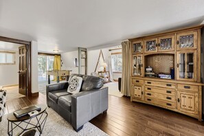 A living room with a leather sofa, a wooden cabinet with glass doors, and a dining area with a table and chairs. - High Point Chateau 4 Bedroom Home by RedAwning (Breckenridge)