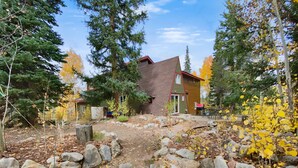 A rustic cabin with a brick exterior, surrounded by a natural landscape with trees and rocks. - High Point Chateau 4 Bedroom Home by RedAwning (Breckenridge)
