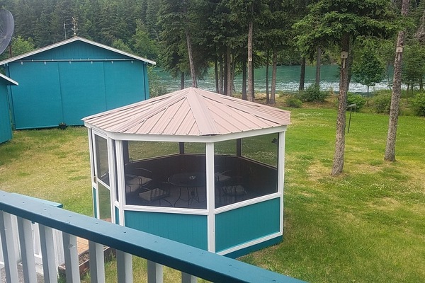 A look off the back porch at the 8-chair screened gazebo and yard to the river