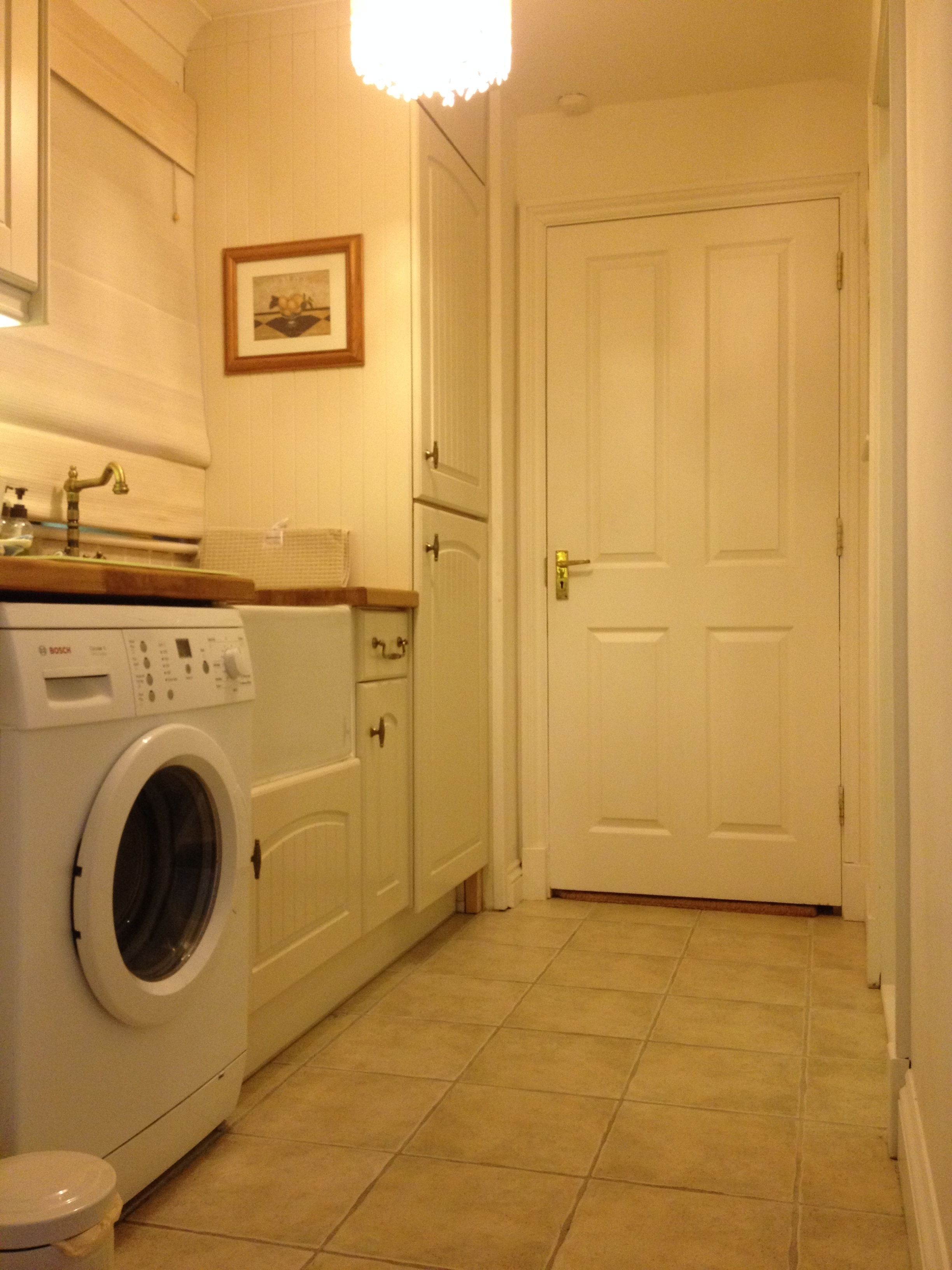 A laundry room with a Bosch washing machine, cabinets, and a door.