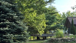Un espace extérieur verdoyant, doté d’une terrasse en bois et d’un mur en pierre.
