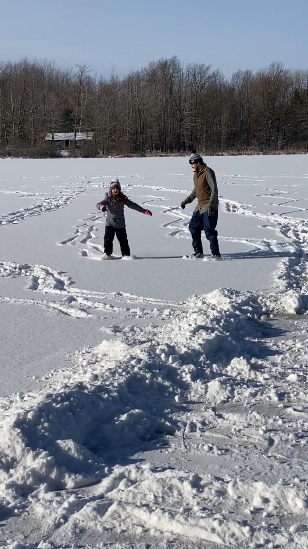 Två personer på en frusen sjö, och i snön syns fotspår.