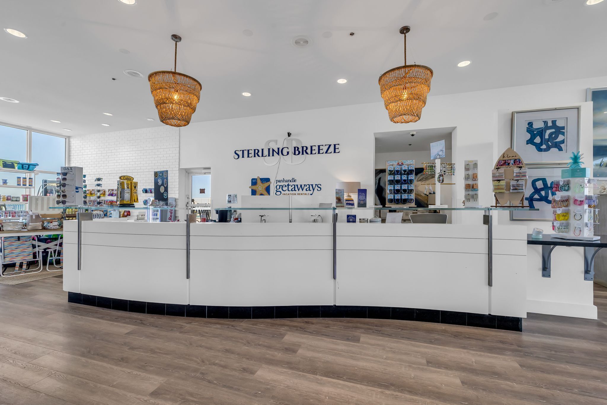 A reception area with a white counter, wicker chandeliers, and a sign for Sterling Breeze Panhandle Getaways.