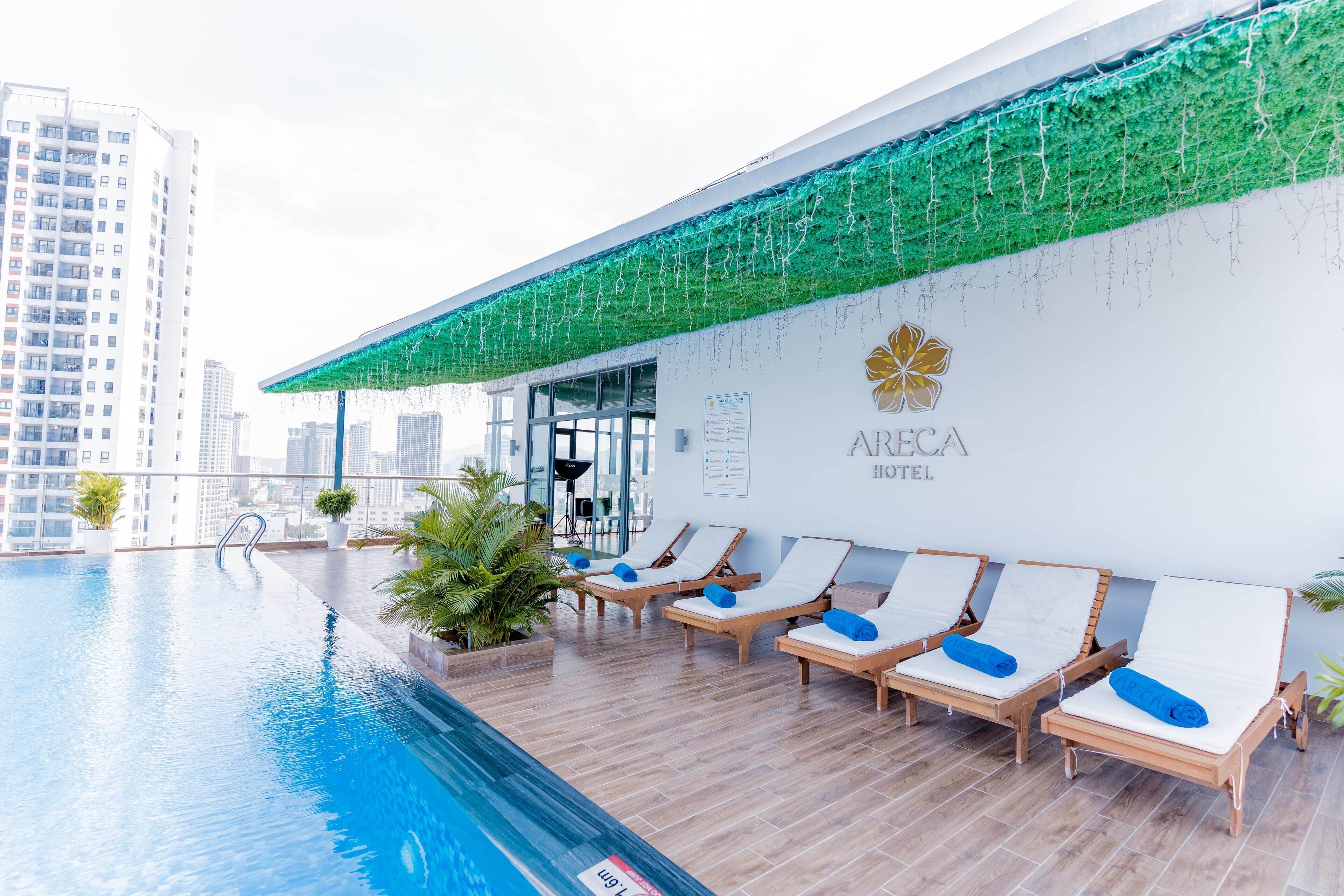 Uma área de piscina no terraço com espreguiçadeiras e uma placa indicando o Hotel Arcea.